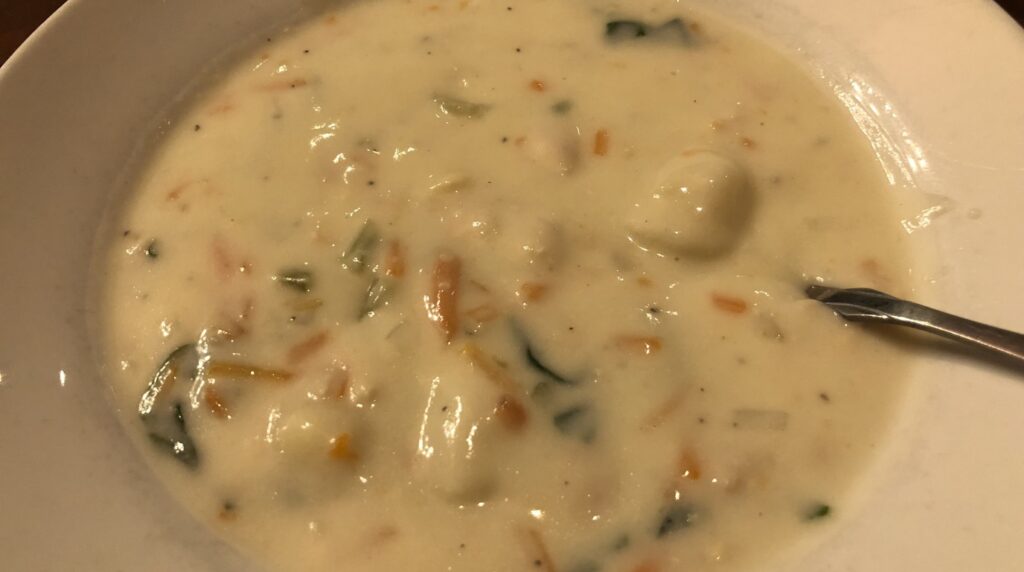 Ultra close-up macro of creamy chicken gnocchi soup with tender chicken, potato gnocchi and fresh spinach