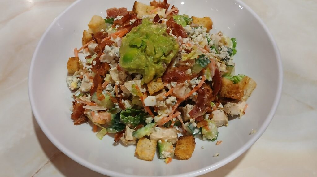 Ultra close-up macro of crispy chicken cobb salad with golden fried tenders, hard-boiled eggs, avocado, crispy bacon and tomatoes