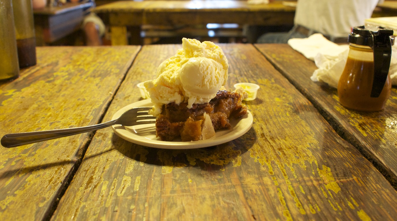 Ultra close-up macro of pecan pie cheesecake with toasted pecans, gooey brown sugar caramel praline and creamy vanilla cheesecake layer
