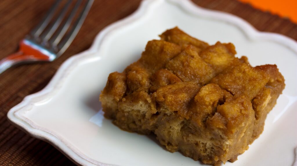Ultra close-up macro of warm pumpkin cream cheese brioche french toast bake with golden toasted brioche edges, spiced pumpkin custard, and sweet cream cheese swirl
